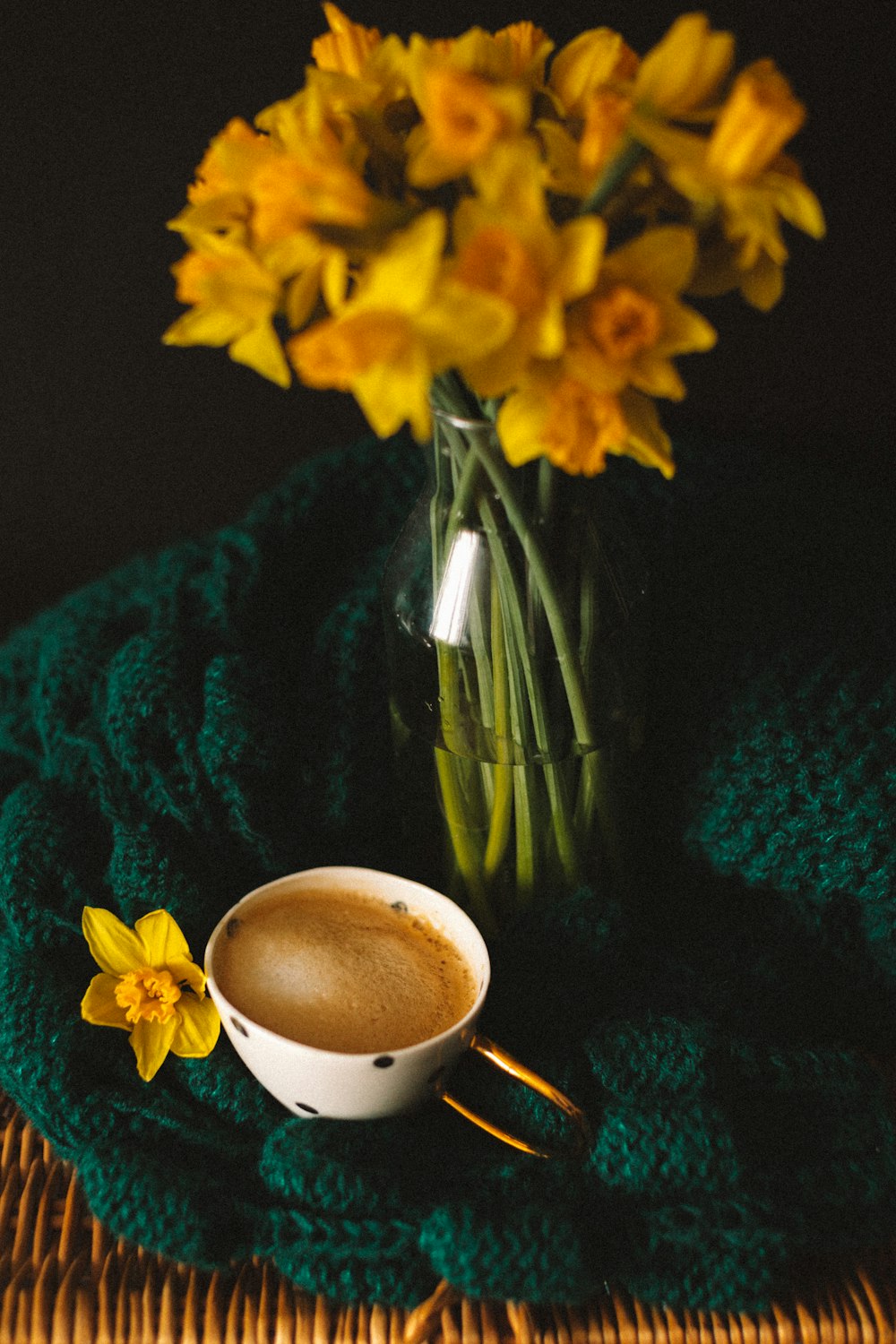 a cup of coffee sitting on top of a table next to a vase of flowers