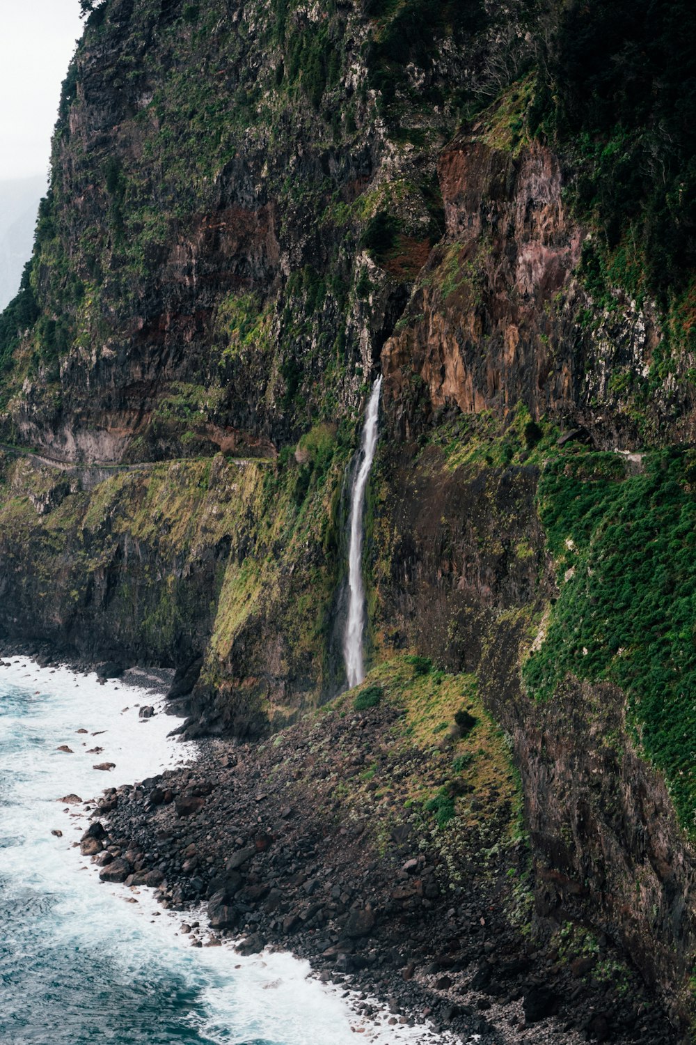 a waterfall on the side of a cliff next to the ocean