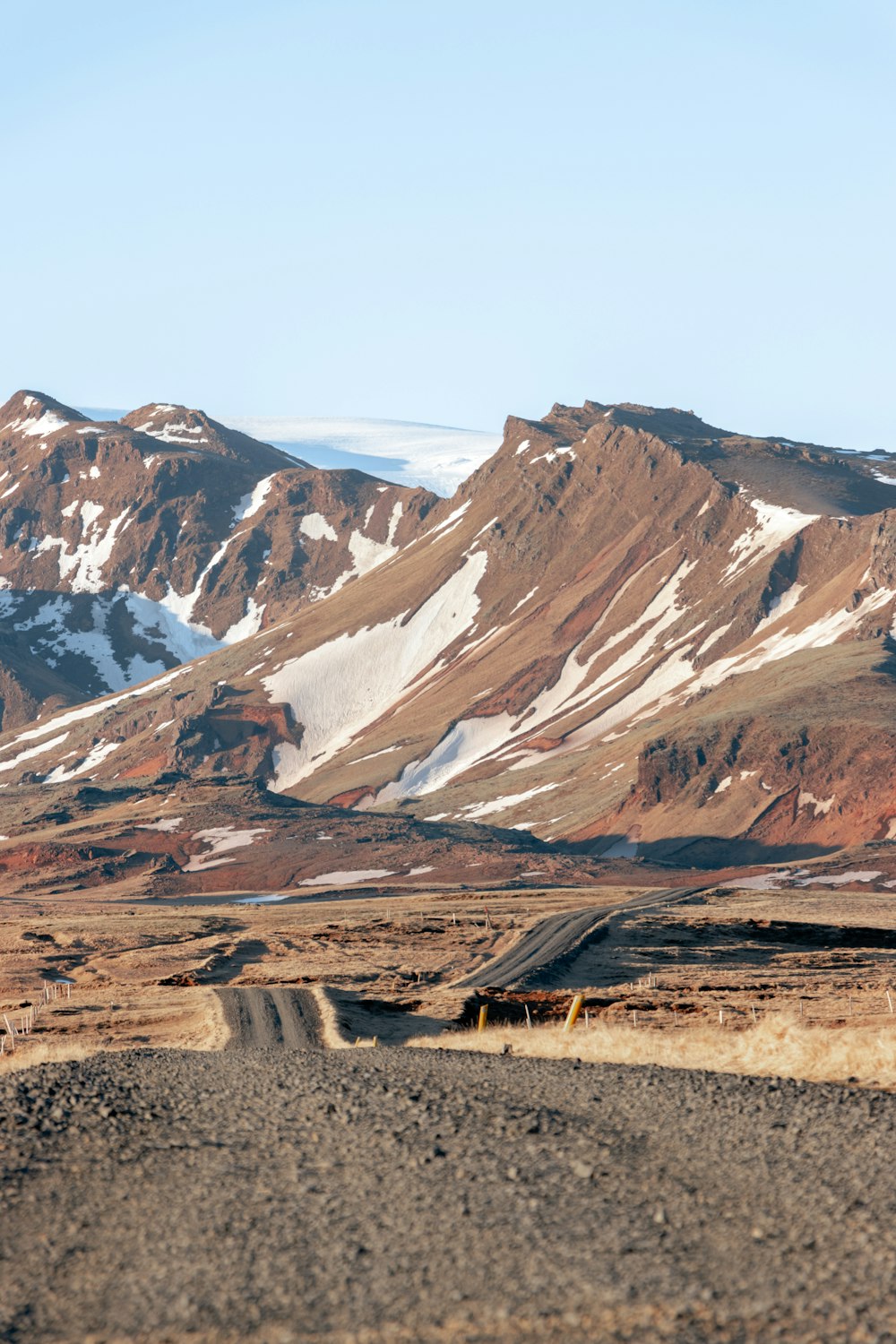 a dirt road in front of a mountain range