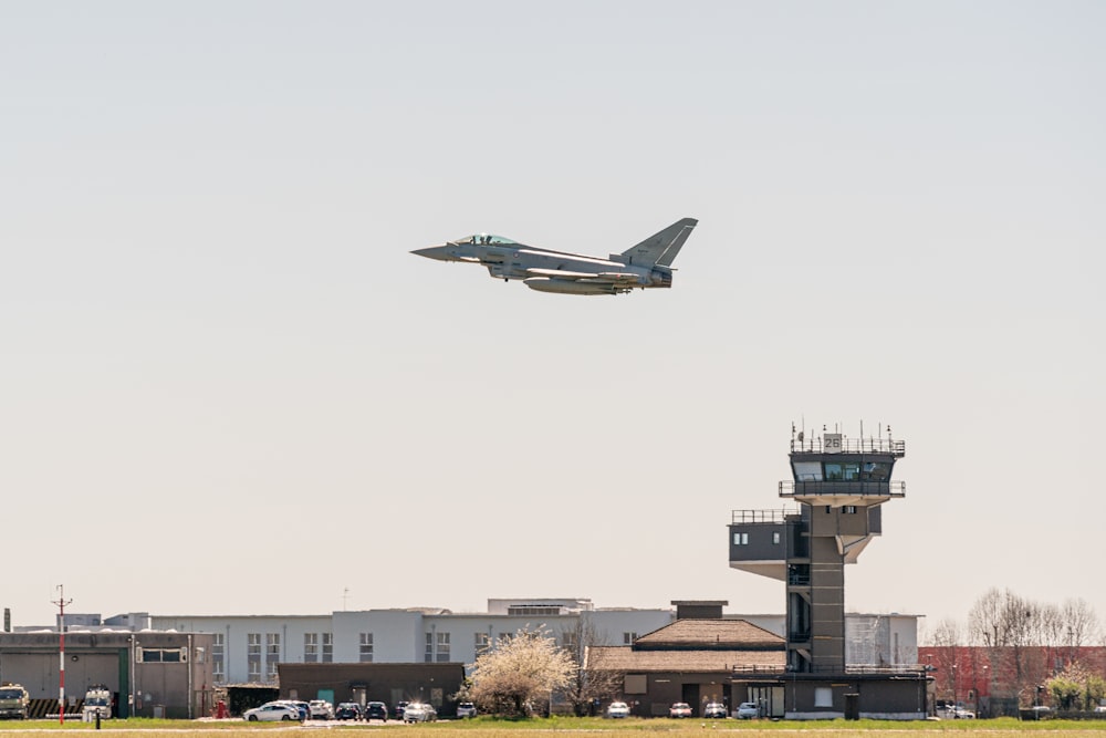 an airplane flying over a building with a control tower