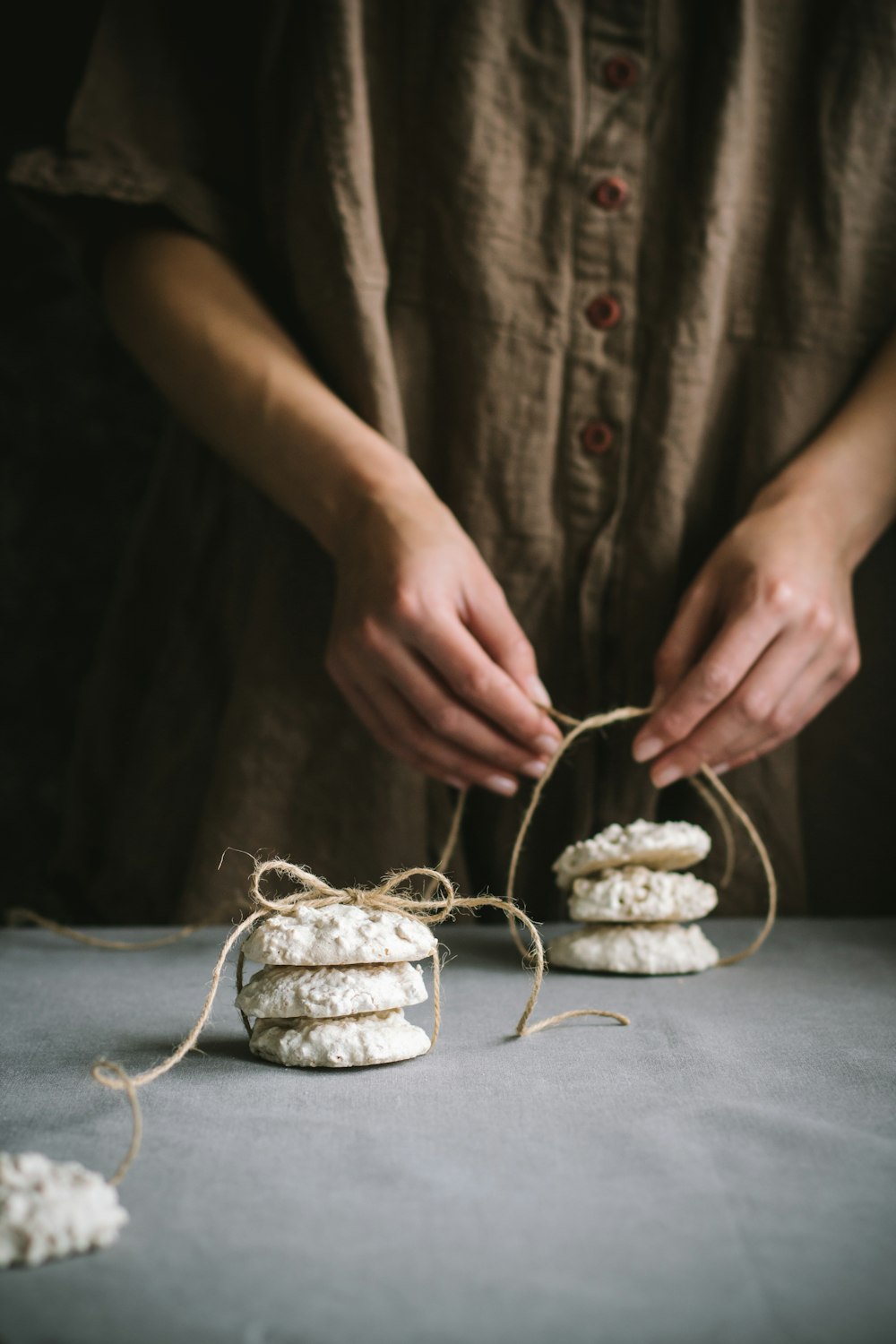 a woman is stringing up some cookies on a table