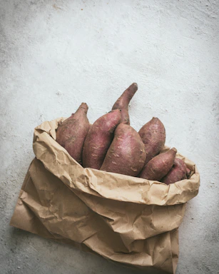 a brown paper bag filled with sweet potatoes