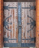 Custom iron door featuring bold vertical bars and a polished metal handle, set against a stone wall.