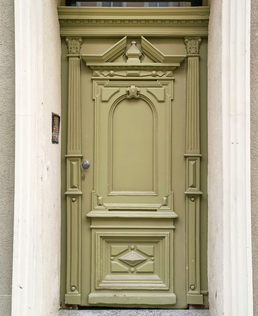 a green door with a clock on the side of it