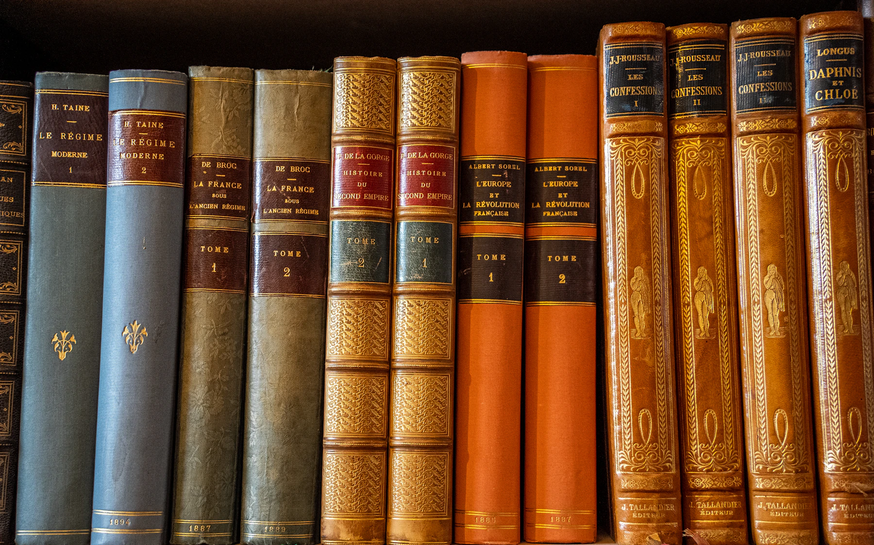 A shelf of old leather-bound French books, their titles and volume numbers stamped in gold on the spines