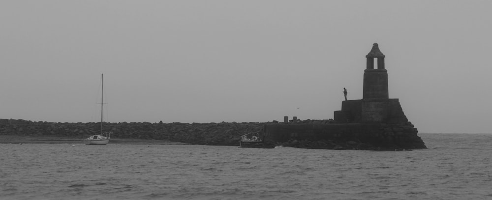 a small boat is in the water near a lighthouse