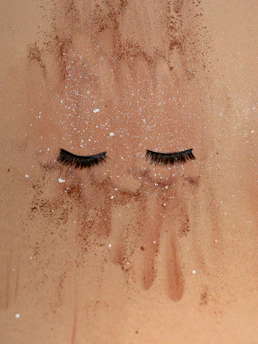 Close-up of elegant false eyelashes displayed on a soft, textured fabric background.