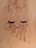 False eyelashes are laid on a sandy surface dusted with specks of brown and white powder.