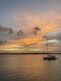 a sailboat in the water at sunset