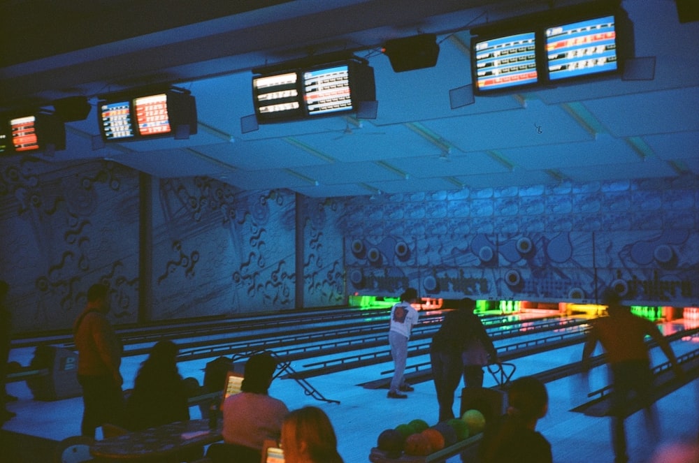a group of people standing around a bowling alley