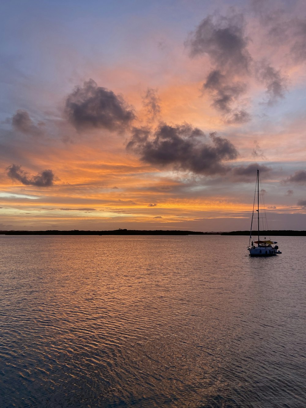 a sailboat in the water at sunset