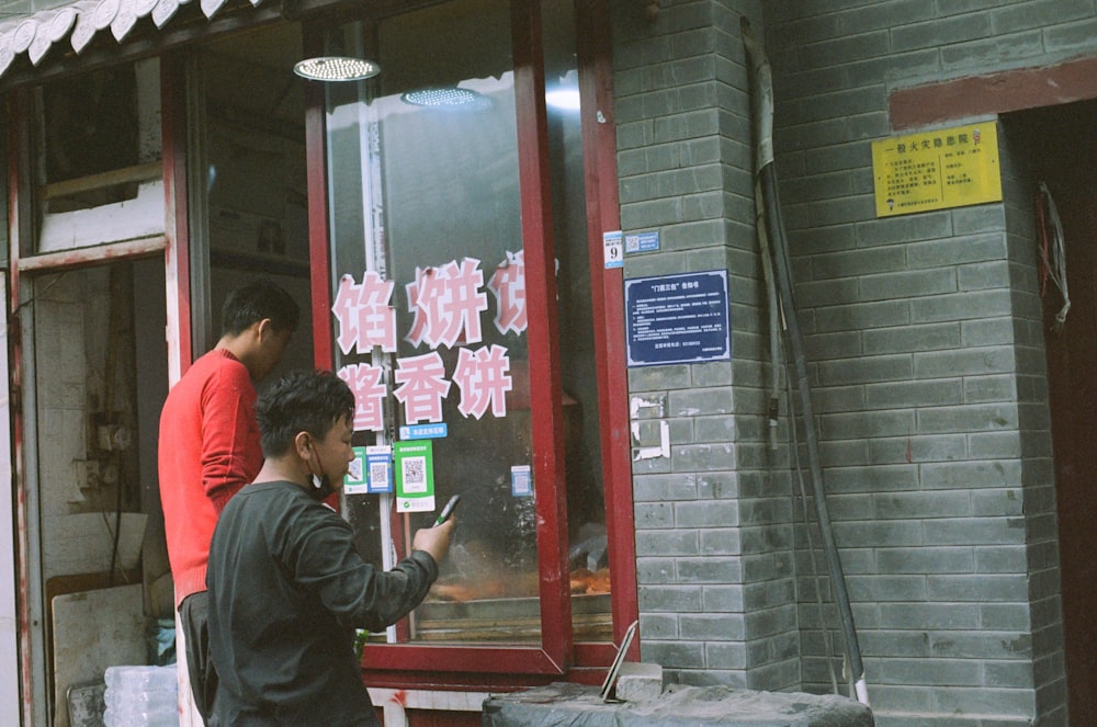 two men standing outside of a store window