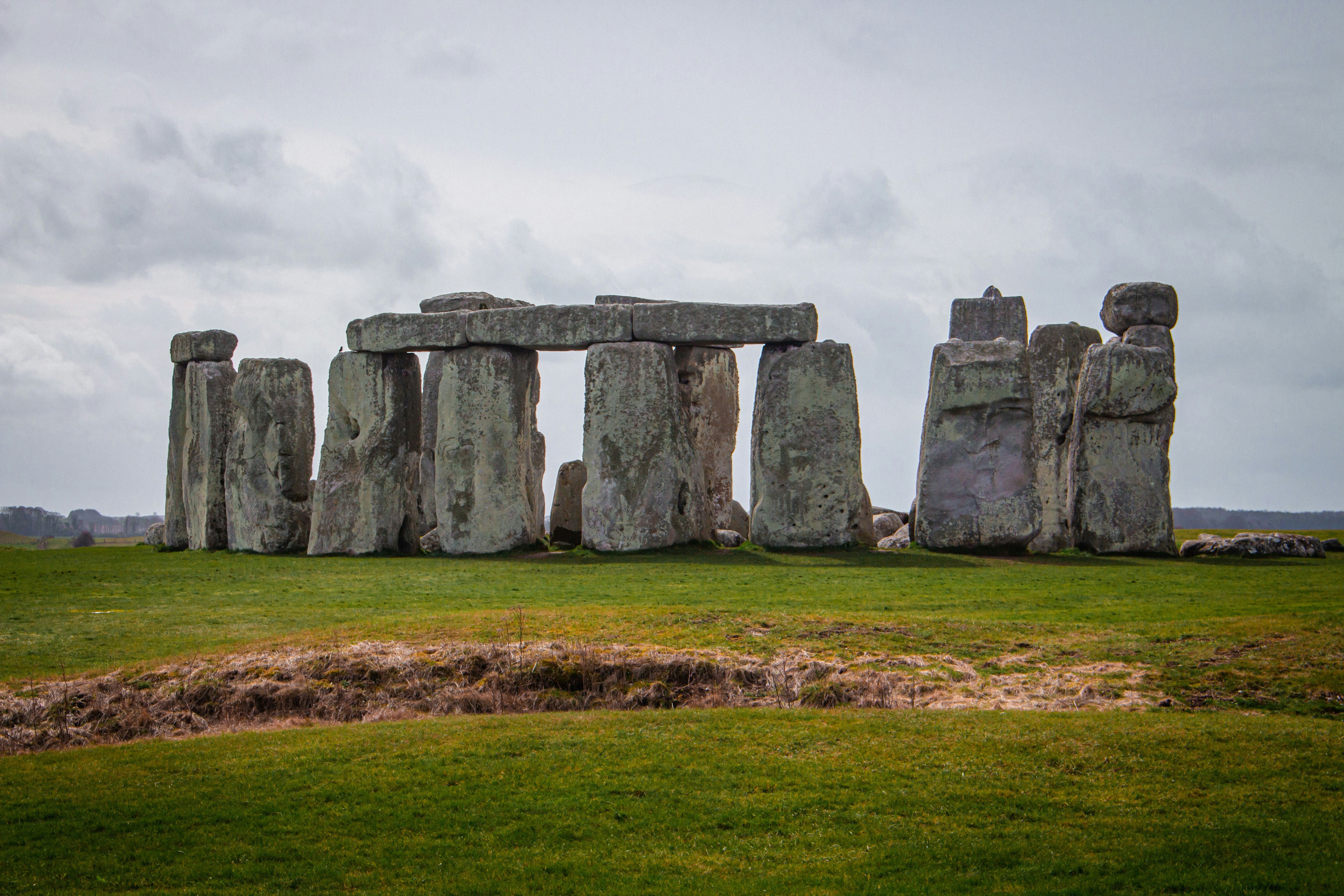 a stonehenge monument in a grassy field, 