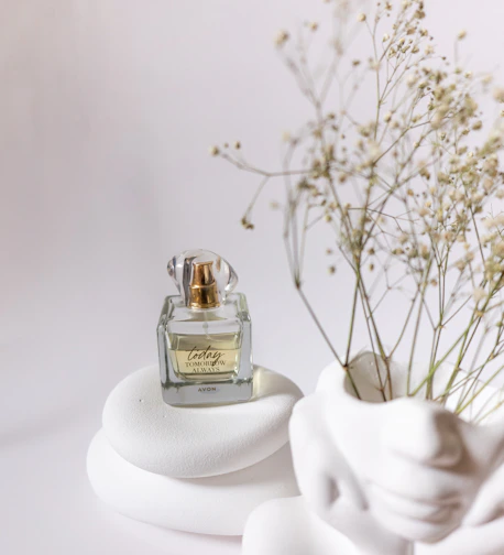 A matte white perfume bottle with minimalist design, placed beside rich oud wood and amber stones.