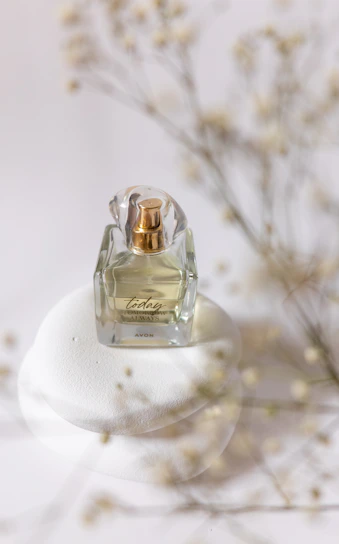 Close-up of a luxurious perfume spray releasing a delicate mist over a white marble surface