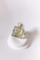 Close-up of a white frosted glass perfume bottle resting on a polished black surface.