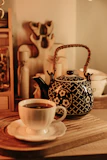 Soft pastel-colored ceramic tea pots and cups set neatly on a warm wooden tray with a glowing candle.