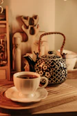 A colorful ceramic teapot with playful patterns sitting beside a steaming cup on a cozy windowsill.