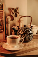 Soft pastel-colored ceramic tea pots and cups set neatly on a warm wooden tray with a glowing candle.