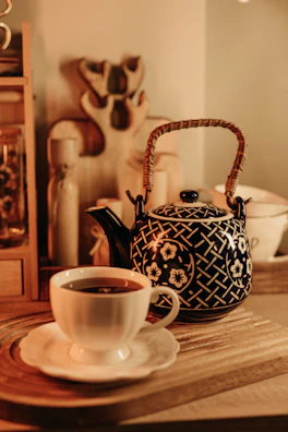 A colorful ceramic teapot with playful patterns sitting beside a steaming cup on a cozy windowsill.