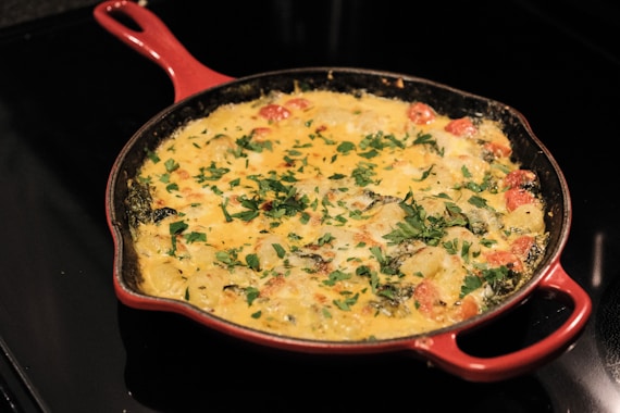 a red pan filled with food sitting on top of a stove