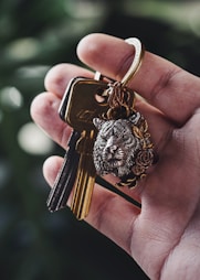 a hand holding a key chain with a lion head on it
