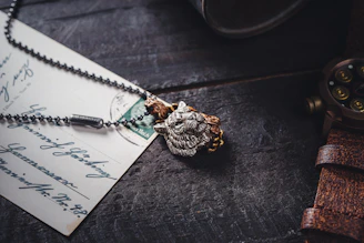 Close-up of a vintage watch and a unique handcrafted necklace displayed on a rustic wooden table.