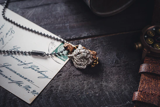 Close-up of a vintage watch and a unique handcrafted necklace displayed on a rustic wooden table.