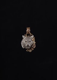 Pendant featuring a wolf’s head carved in dark metal with intricate detail.