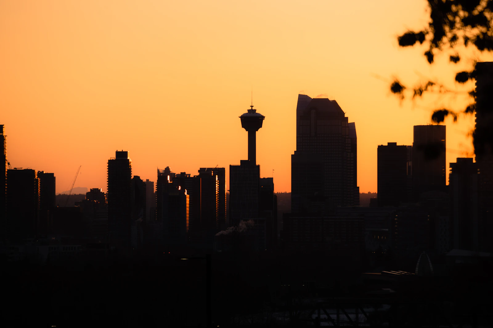 The downtown Calgary skyline glowing against a vivid orange sunset sky