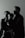 A family of three is captured in a side profile shot. The adults are looking in the same direction, with a child in the arms of one of the adults. They appear to be indoors, and the lighting creates a dramatic, shadowed effect on their faces.