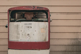 Close-up of a vintage gas pump showcasing rust textures alongside polished chrome details under moody industrial lighting.