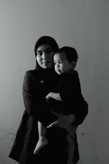 African woman confidently holding a child, natural light, warm tones, documentary style