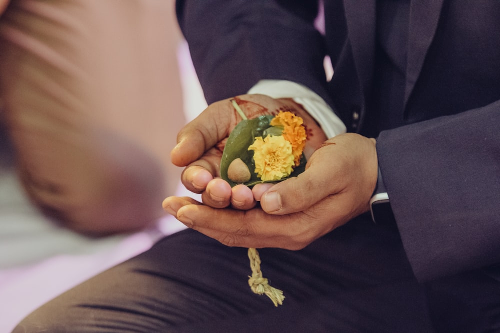a man in a suit holding a flower in his hands
