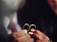 a close up of a person holding two wedding rings
