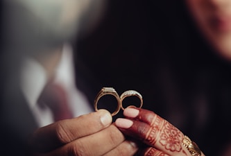 a close up of a person holding two wedding rings