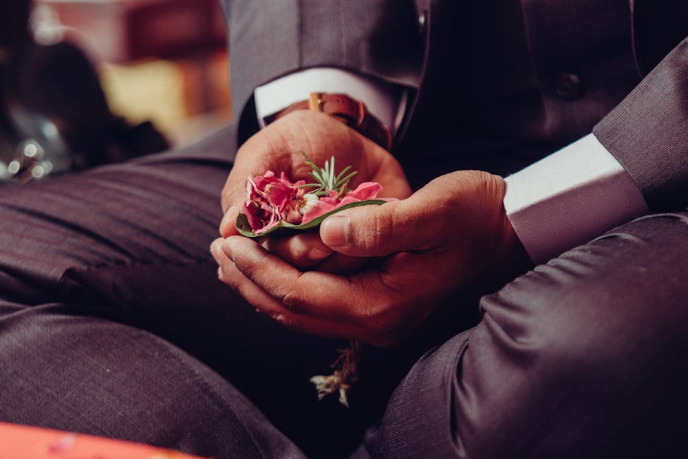 a man in a suit is holding a flower