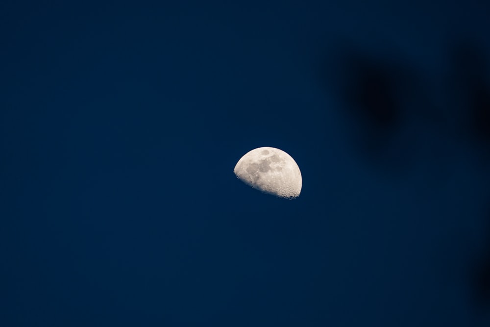 a half moon is seen in the dark blue sky