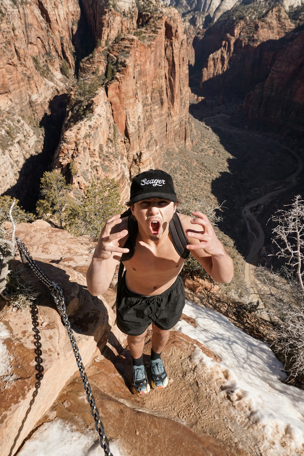 a man is standing on a rock ledge with his hands in the air