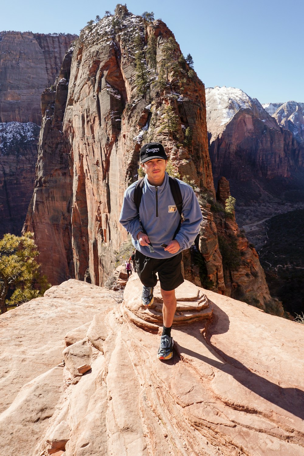 a man standing on top of a mountain next to a cliff