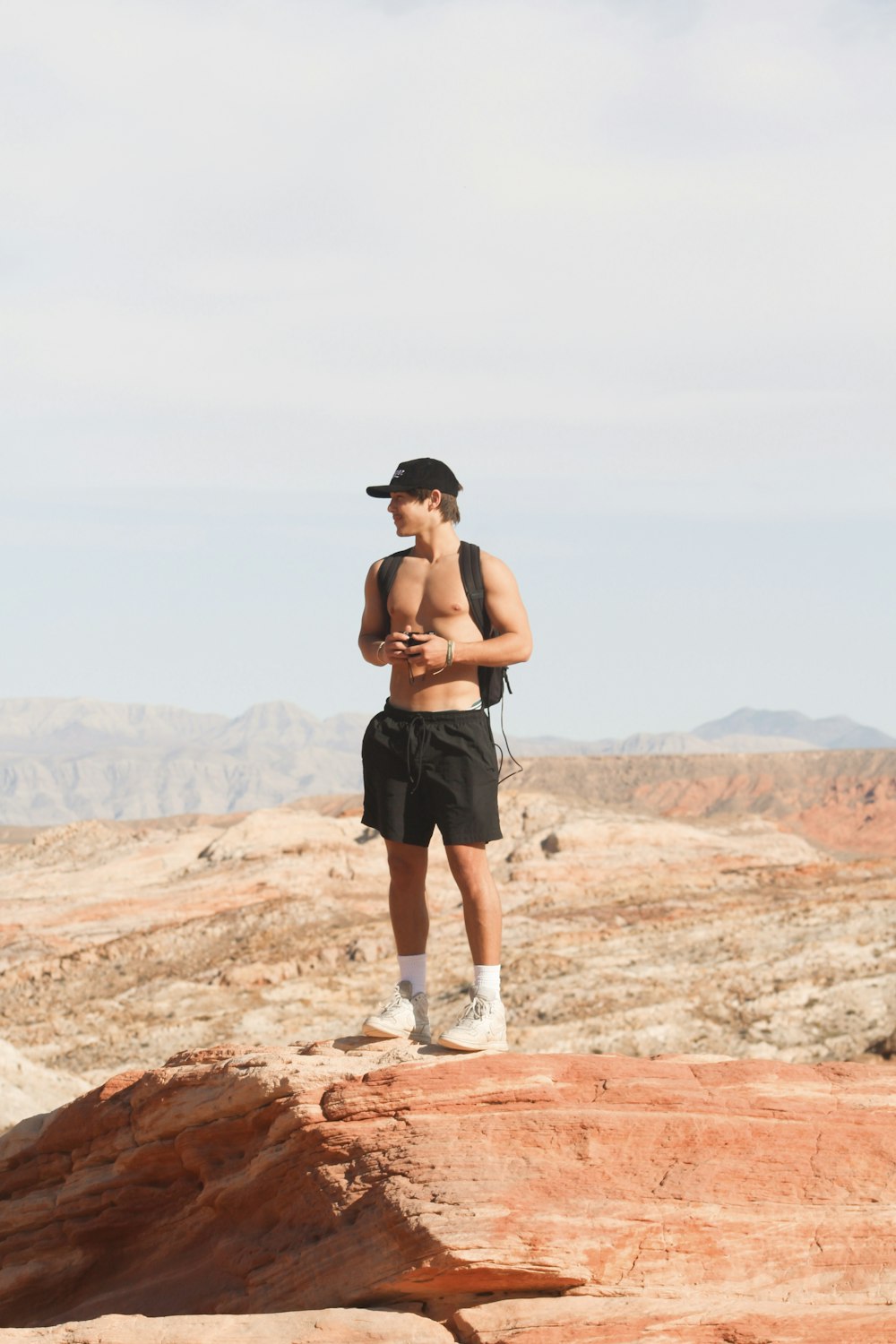 a shirtless man standing on top of a rock