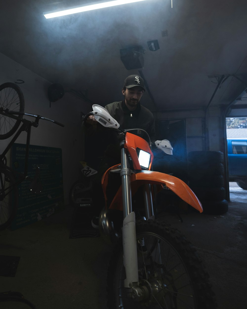 a man sitting on a dirt bike in a garage