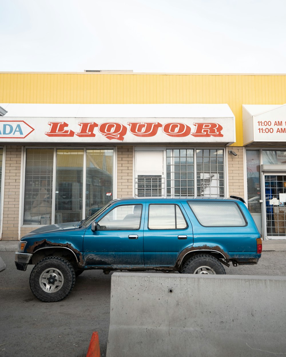 a blue truck parked in front of a liquor store