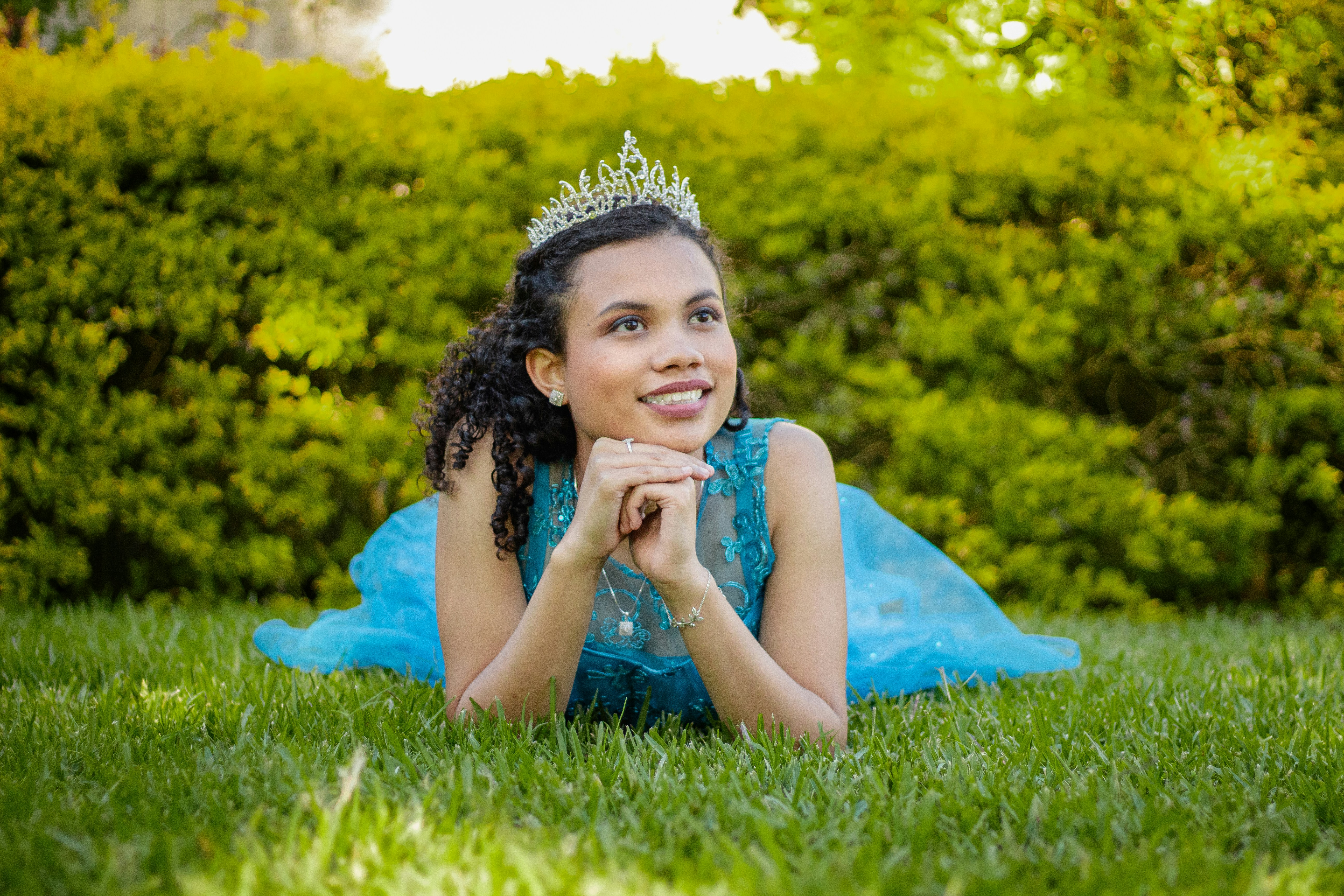 a woman laying on the grass wearing a tiara