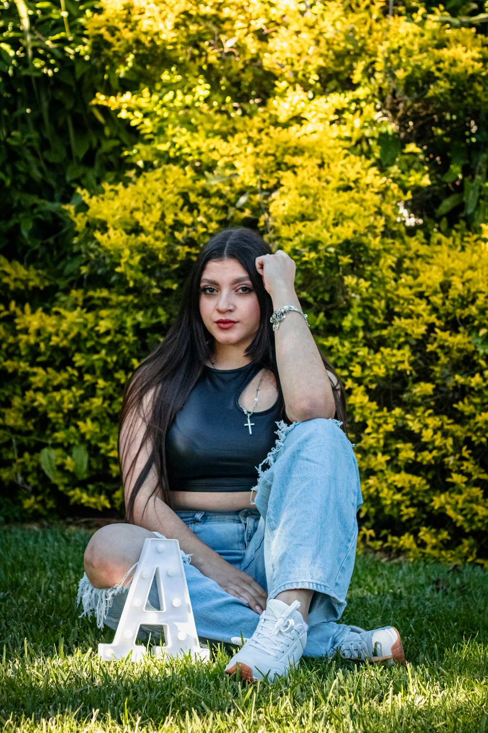 a woman sitting in the grass with her arms behind her head