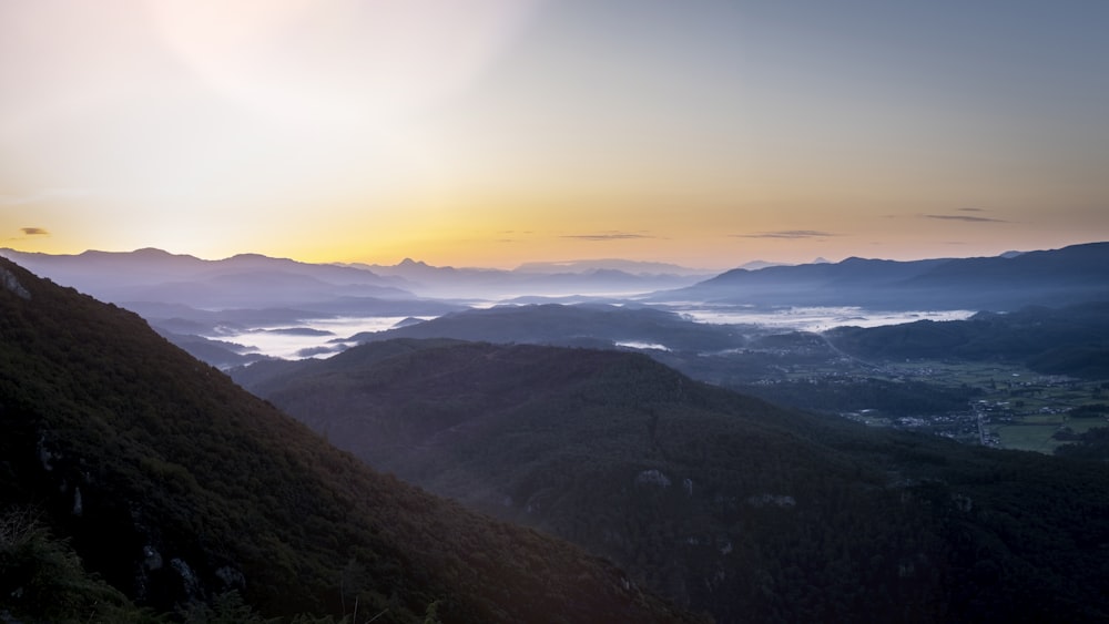 the sun is setting over a mountain range