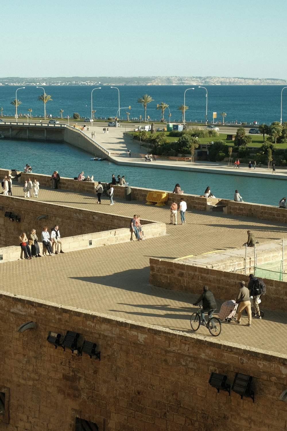 a group of people walking and riding bikes near a body of water