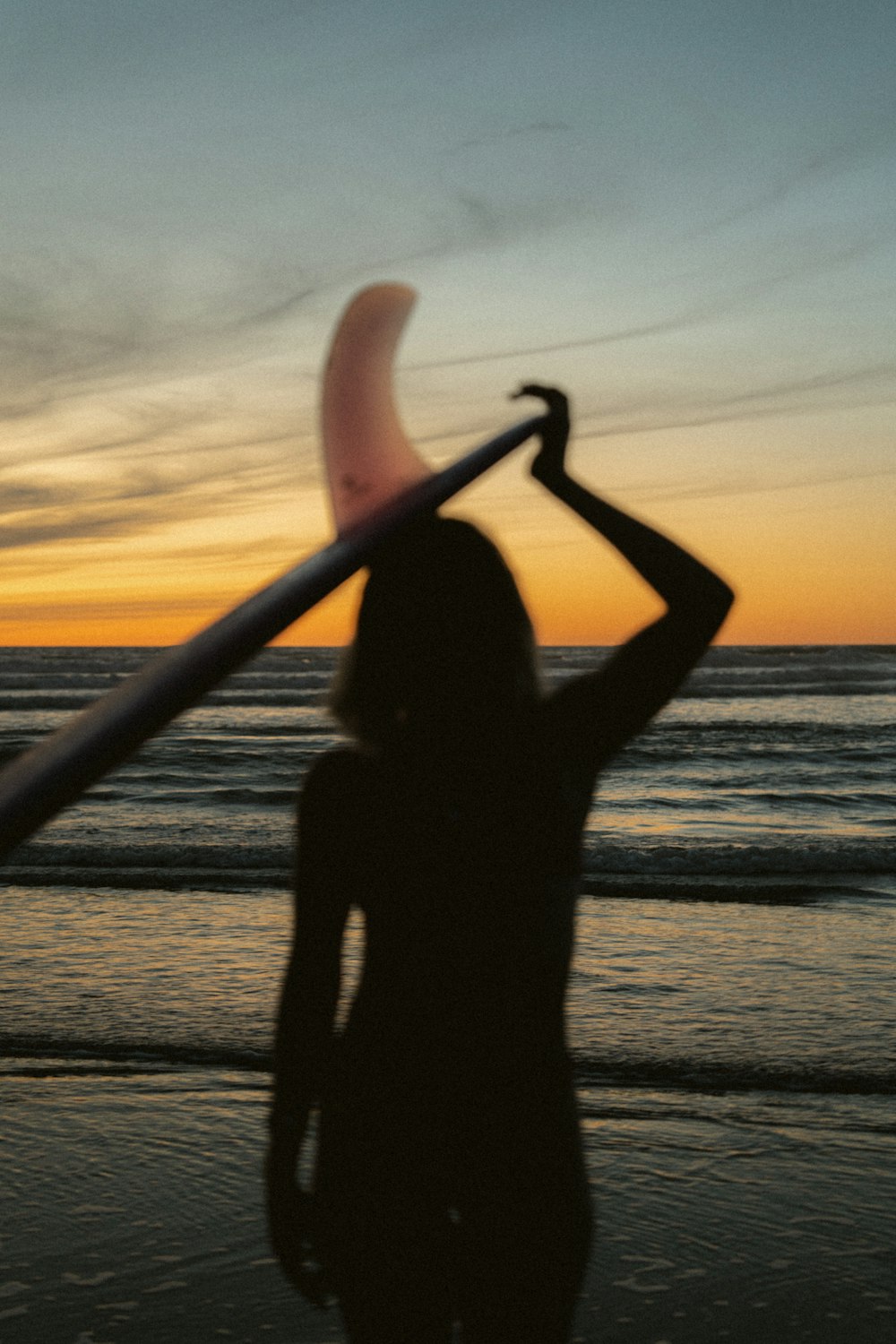 a woman holding a surfboard on top of a beach