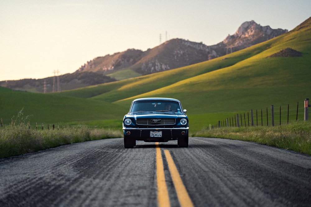 a classic car driving down a country road