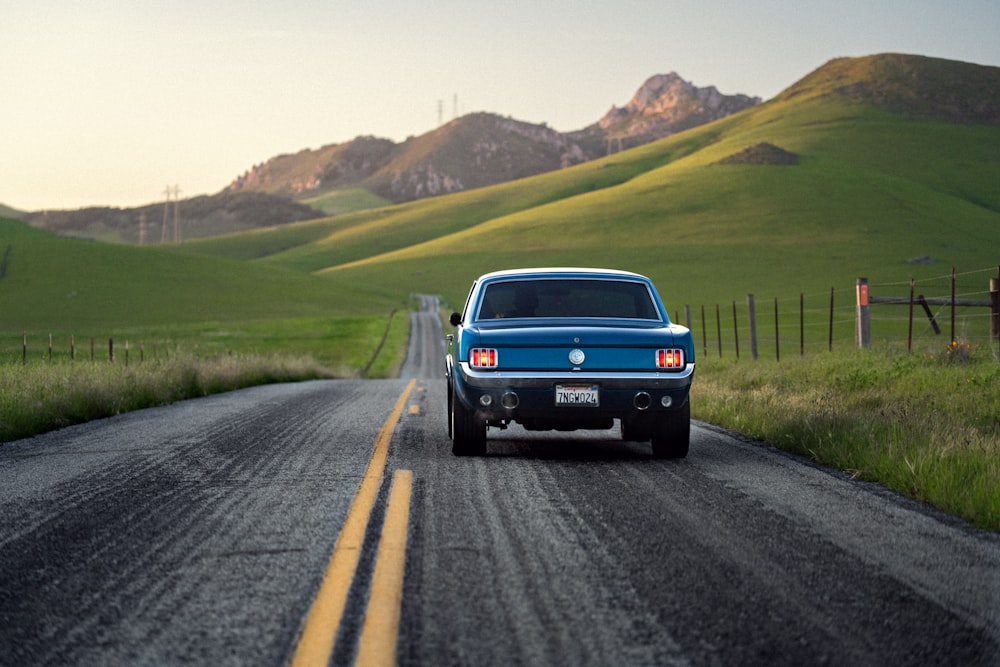 a blue pickup truck driving down a country road